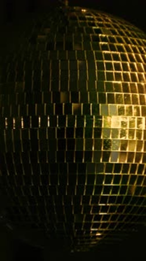 Shimmering disco ball reflects vibrant light. Vertical