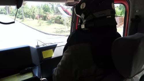 Professional Fireman in Uniform Riding on a Big Truck to Place of a Fire Young Male Firefighter in