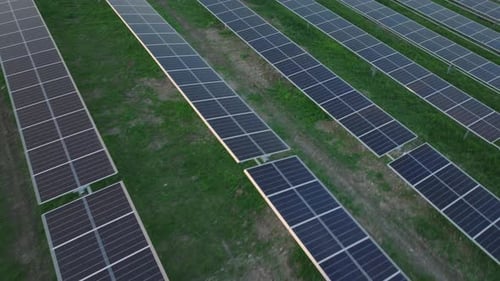 Aerial view of rows of solar panels installed on a green field for clean energy production