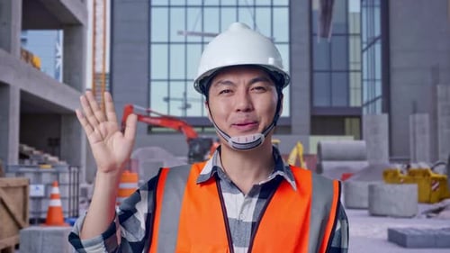 Asian Male Engineer Smiling To Camera And Waving Hand Saying Bye at Construction Site