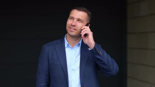 Close Up Portrait of Handsome Cheerful Businessman Speaking on Mobile Phone While Standing Near