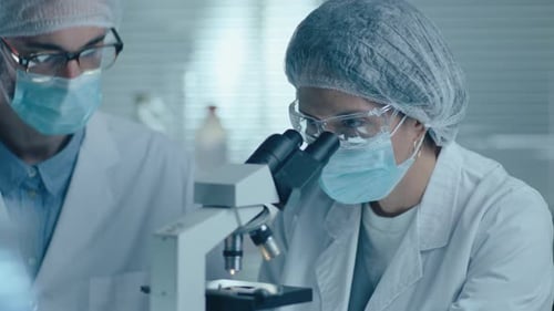 Scientists Using Microscope in a Brightly Lit Lab