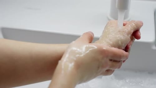 Woman washing her hands in bright bathroom sink