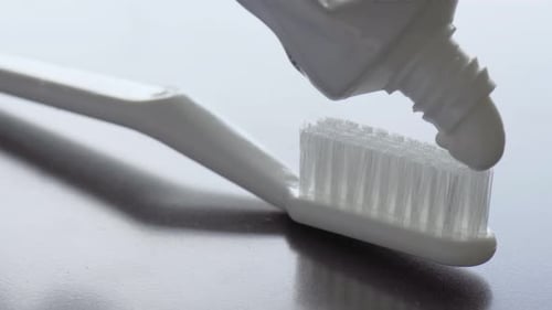 Toothpaste is being squeezed on toothbrush. Close-up footage