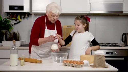 Liebevolle, glückliche Großmutter bringt niedlichen Kindern bei, wie sie Teig kneten, backen, Gebäck backen, modern lernen