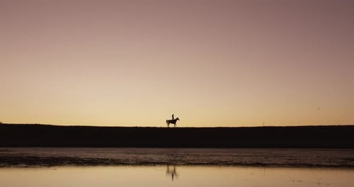 4k-Videomaterial einer silhouettierten Frau, die bei Sonnenuntergang auf einer Ranch auf einem Pferd reitet