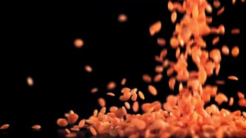 Vibrant Orange Lentils Cascading Down on Black Surface