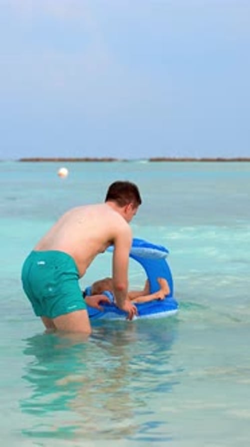 Vertical of Joke Father Pushes the Child Out on Swimming Circle and Waves at Him and Leaves