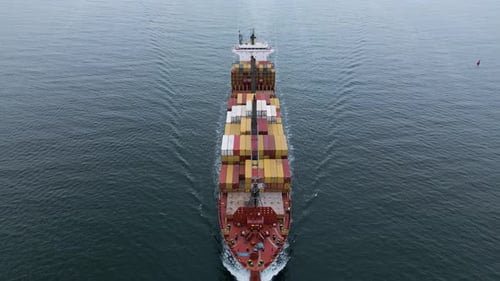 Aerial View of a Large Cargo Ship Sailing Through Calm Sea with Colorful Containers on Deck Maritime