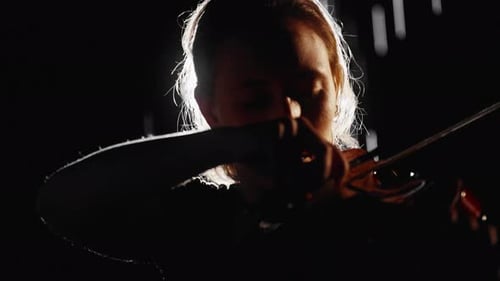 Woman Plays the Violin in Dark Room