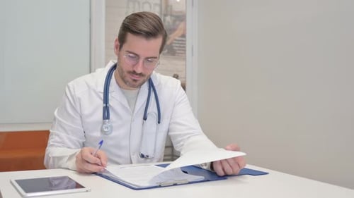 Middle Aged Doctor Working on Documents in Clinic