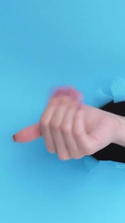 Hand Gesturing in Front of Torn Blue Paper
