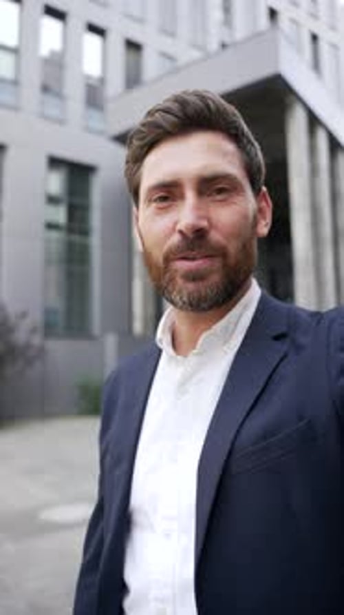 Happy Businessman Waving in Front of Modern Building