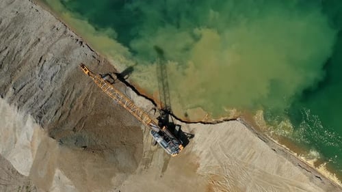 Aerial view of excavator moving sand and gravel on the lakeside, heavy industry and construction equ