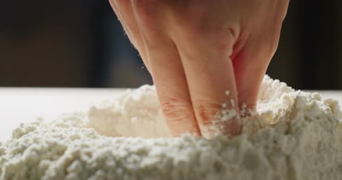 Ein Bäcker bereitet das Mehl auf seinem traditionellen Holztisch zu und bohrt mit seiner Hand ein Loch, in das