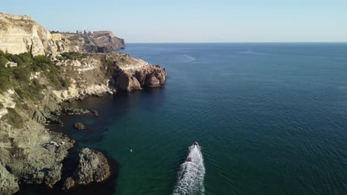 Coastal Cliffs and Speedboat on Clear Waters