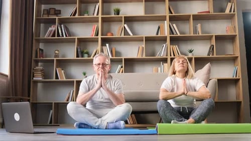 Senior Couple Meditating in Home Yoga Session