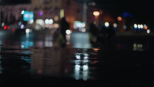Nighttime City Street with Blurred Reflections and Pedestrians