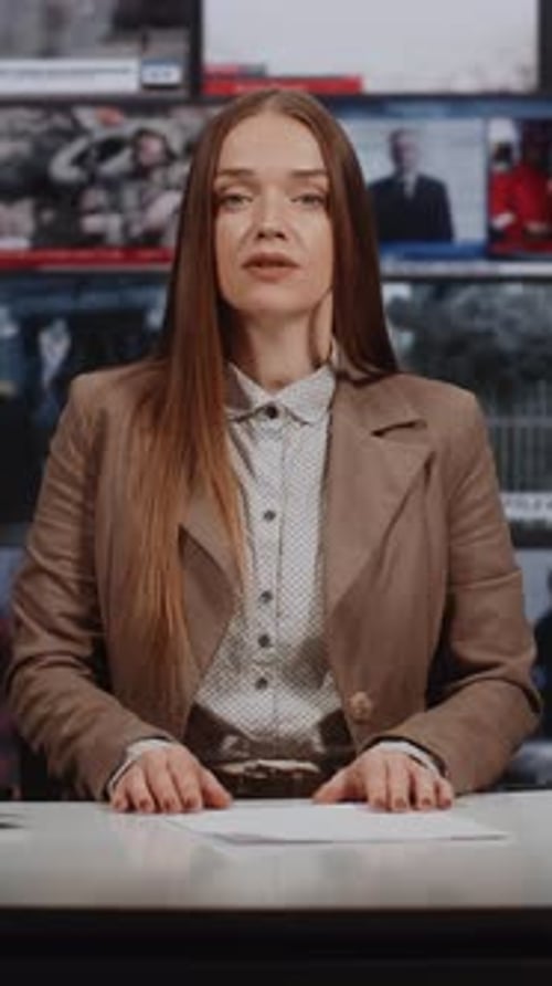 Female Newscaster Presents News in Front of Monitors