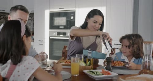 Happy Family Eating Spaghetti at Kitchen Table