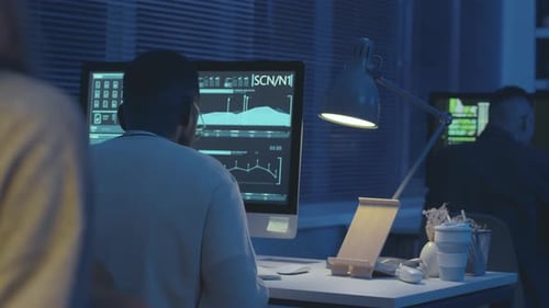 Cybersecurity Workers Monitoring Data in Office at Night