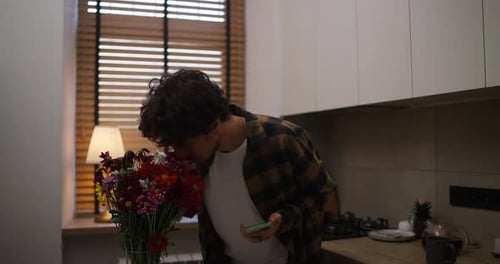 Young Adult Smelling Flowers in Modern Kitchen