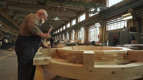 A Skilled Craftsman is Diligently Working on a Large Wooden Structure Inside His Workshop Stock Clip