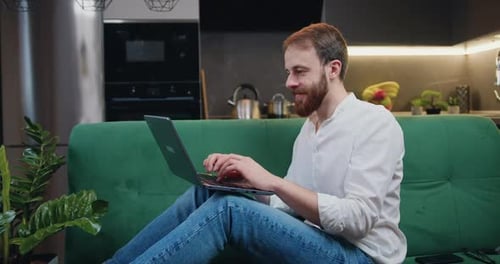 Lächelnder Mann, der Laptop benutzt, um E-Mail-Nachrichten zu checken oder in sozialen Netzwerken im Internet nach Freunden zu suchen