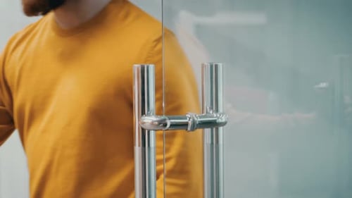 Footage of a Person Opening a Clear Glass Door With Metal Handles in a Modern Building in Broad