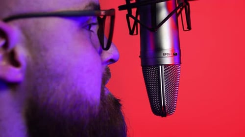 Man Speaking in Front of Professional Microphone With Red Background