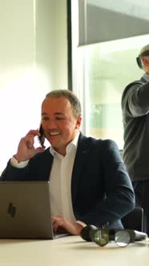 Man On Phone Working On Computer