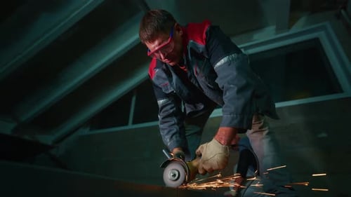 Individual Crafts Metal Panel Beneath Lights Skilled Worker Uses Grinder to Shape Metal Roofing