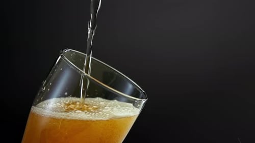 Beer Pouring into Glass Overflowing with Foam