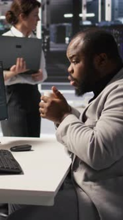 Vertical Video Stressed Technician in Data Center Managing AI Servers Drinking Coffee