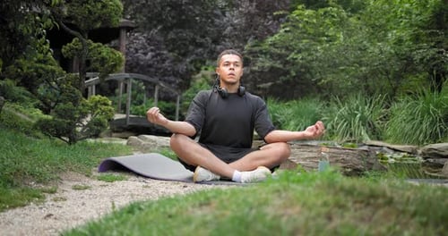 Young African American Spirituality Man Meditating Yoga Asana Sitting in a Park Outdoor