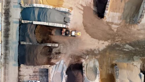 Aerial View of Industrial Construction Yard Showing a Wheel Loader Moving Between Large Piles of