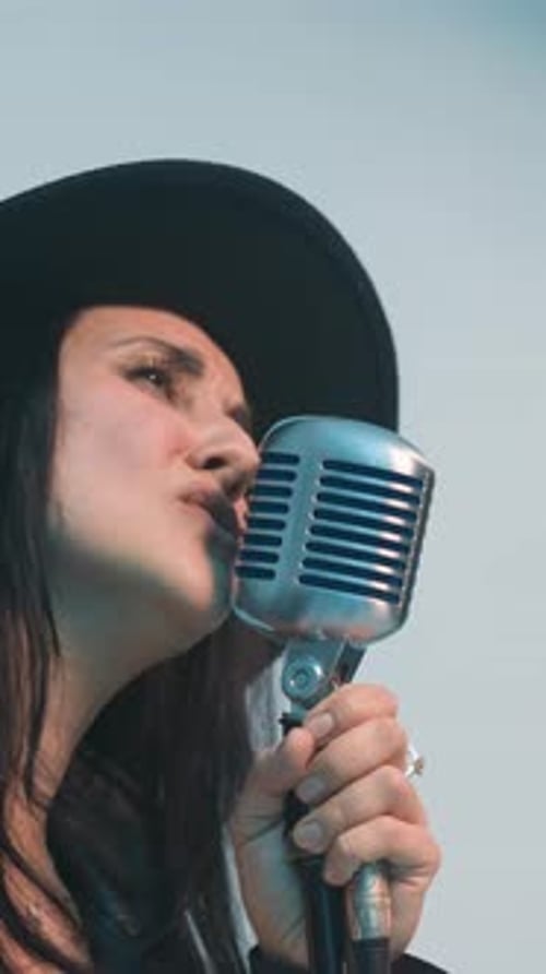 Woman singing into vintage microphone close up