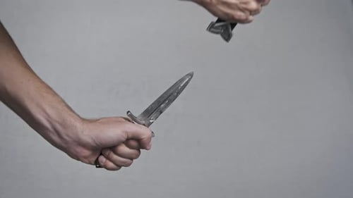 Man Opens Dagger Blade with Two Hands