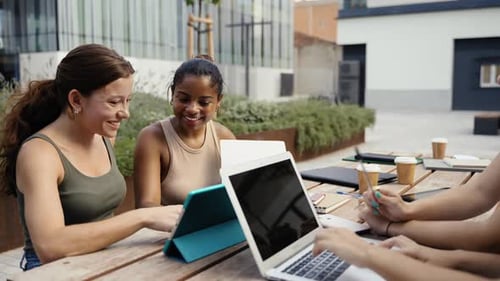 Young Adults Collaborating on Tech Devices in Urban Setting