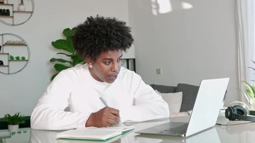 Young Adult Studying with Laptop and Notebook