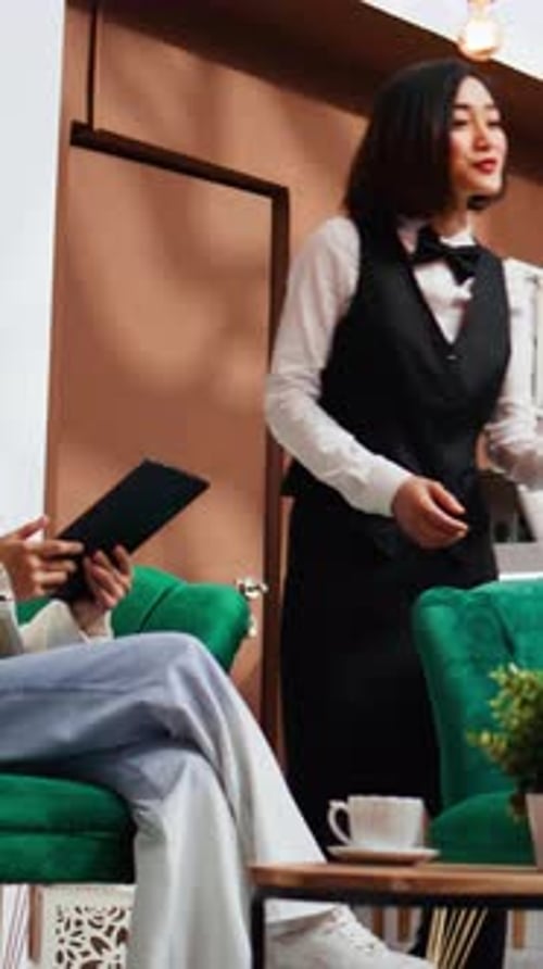 Vertical Video Employee Offering Information to Asian Tourists in Lobby