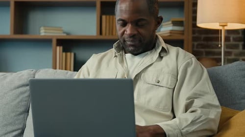 Glücklicher afroamerikanischer Mann, Geschäftsmann, Freiberufler, beendet Computerarbeit, schließt Laptop zu Hause, Job gut