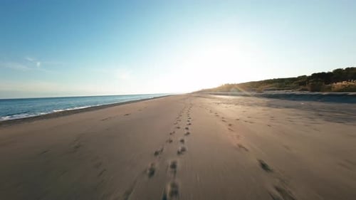 Flying Over Sandy Beach at Sunset