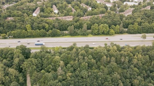 A busy highway near Munich. Aerial view of the traffic. Freeway leads through a forest past suburbs.