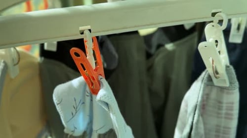 clothespins and garments hanging on indoor laundry rack in daylight