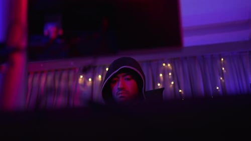 Man in Hoodie Illuminated by Neon Lights