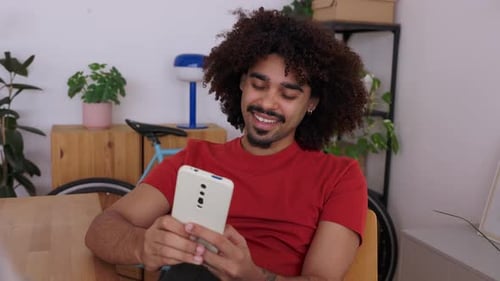 Smiling Man Relaxing on Sofa Looking at Phone