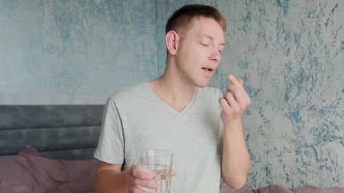 Young Adult Man Taking Pill With Water