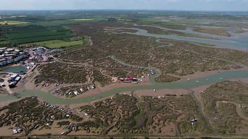 Descending aerial view of Tollesbury lightship landmark on Essex marina marshland estuary veins