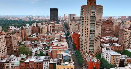 Flying above the tops of low multistoried buildings of New York and long highway.